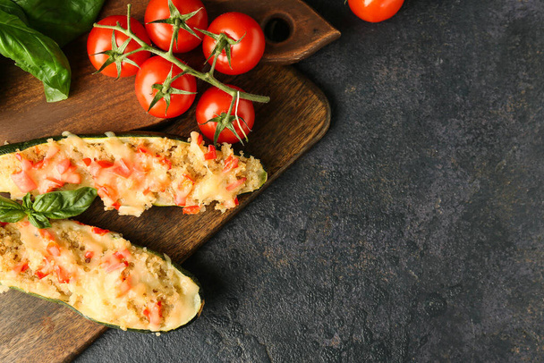 Houten bord met quinoa gevulde courgettes en verse tomaten op donkere ondergrond - Foto, afbeelding