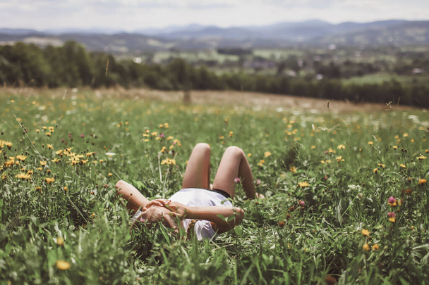 朝山の頂上の緑の芝生でリラックスした魅力的な女の子 - 写真・画像