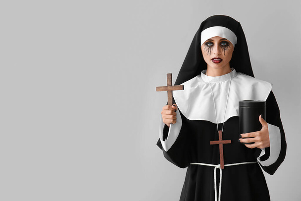 Kobieta ubrana na Halloween jako zakonnica z urną kostnicy na jasnym tle - Zdjęcie, obraz