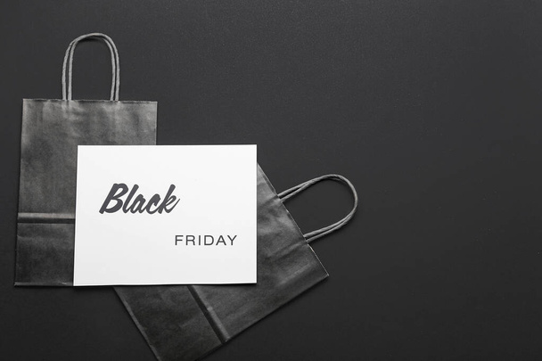 Card with text BLACK FRIDAY and shopping bags on dark background - Foto, afbeelding