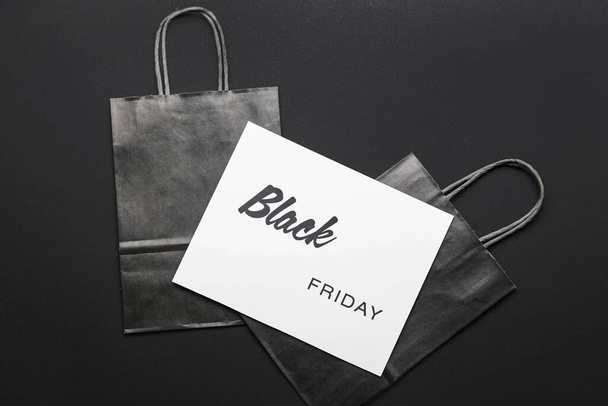Card with text BLACK FRIDAY and shopping bags on dark background - Foto, Bild
