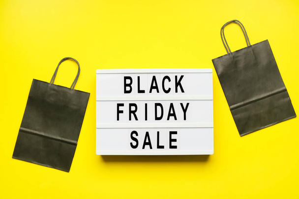Shopping bags and board with text BLACK FRIDAY SALE on color background - Photo, Image