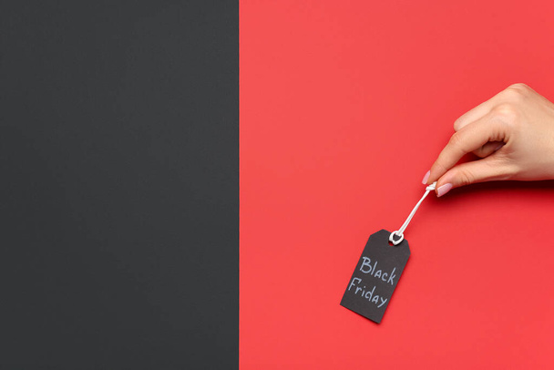 Γυναικείο χέρι και ετικέτα με κείμενο ΜΑΥΡΟ ΠΑΡΑΣΚΕΥΗ σε έγχρωμο φόντο - Φωτογραφία, εικόνα