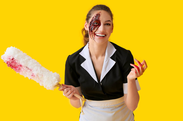 Frau zu Halloween als Zimmermädchen verkleidet mit Staubpinsel auf farbigem Hintergrund - Foto, Bild