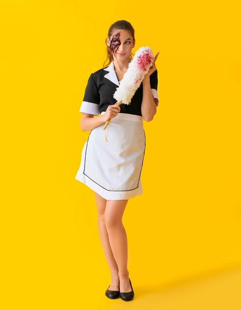Mujer vestida para Halloween como camarera con pincel de polvo sobre fondo de color - Foto, imagen