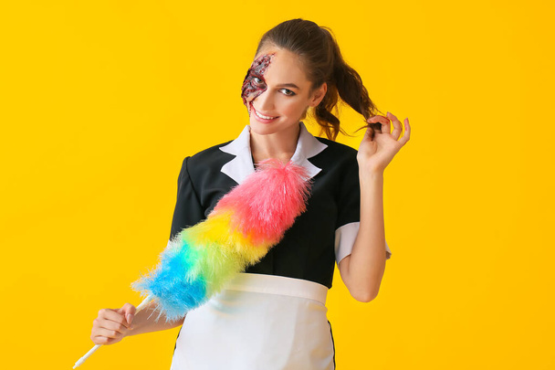 Woman dressed for Halloween as chambermaid with dust brush on color background - Φωτογραφία, εικόνα