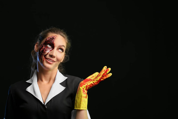 Mujer vestida para Halloween como camarera mostrando algo sobre fondo oscuro - Foto, imagen