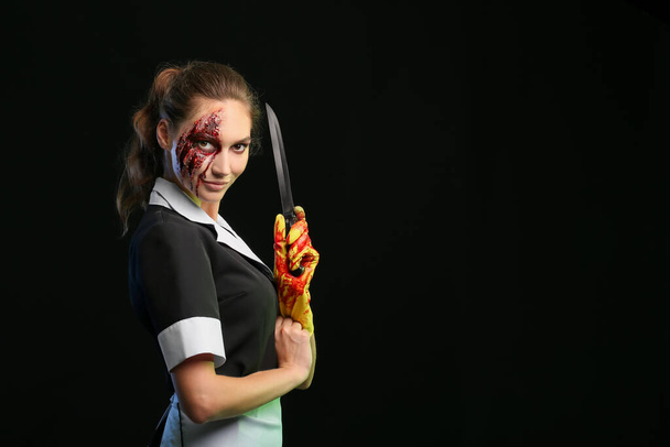 Žena oblečená na Halloween jako pokojská s nožem na tmavém pozadí - Fotografie, Obrázek