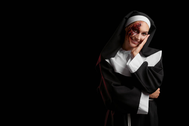 vrouw gekleed voor Halloween als non op donkere achtergrond - Foto, afbeelding