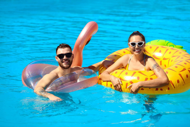 Young couple with inflatable rings in swimming pool - Photo, Image