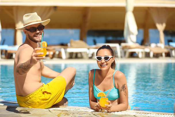Jeune couple avec cocktails près de la piscine - Photo, image