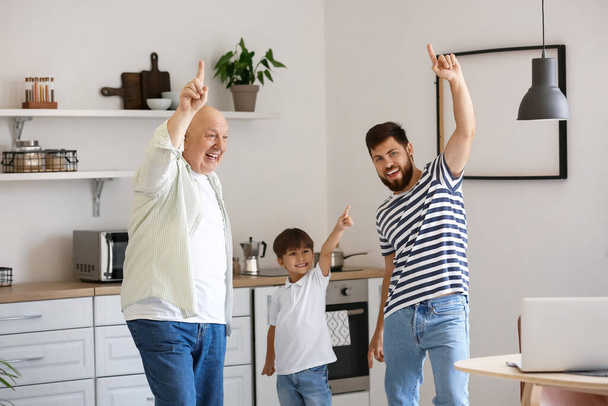 Ευτυχισμένος άνθρωπος, ο μικρός γιος και ο πατέρας του χορεύουν στην κουζίνα. - Φωτογραφία, εικόνα
