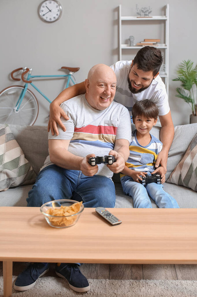 Amico, suo figlio e suo padre che giocano ai videogiochi a casa - Foto, immagini