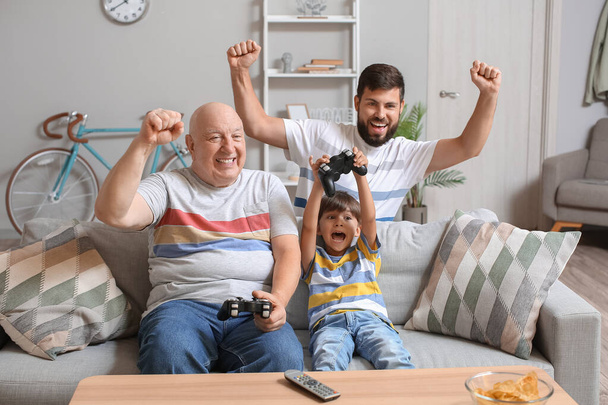 Chłopie, jego synek i ojciec grają w gry wideo w domu. - Zdjęcie, obraz
