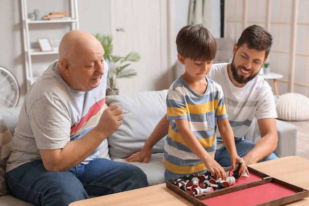 Man, zijn zoontje en vader spelen thuis schaak. - Foto, afbeelding
