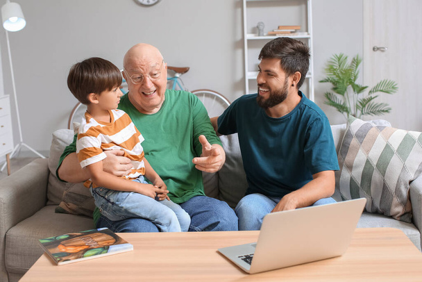 Onnellinen mies, hänen pieni poikansa ja isänsä video chattailuun kotona - Valokuva, kuva