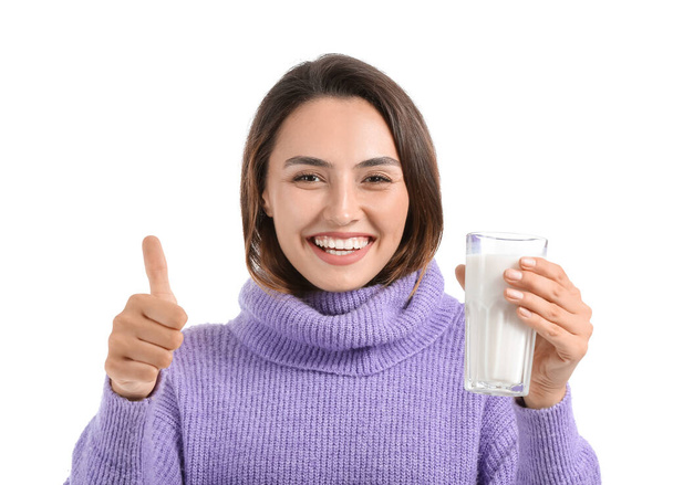Junge Frau mit Glas frischer Milch zeigt Daumen nach oben auf weißem Hintergrund - Foto, Bild