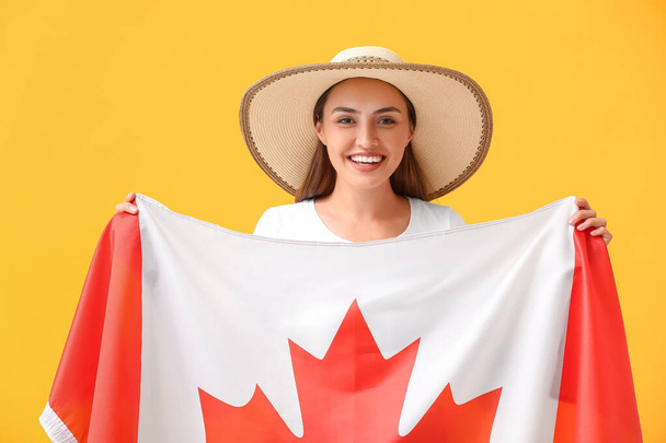 色の背景にカナダの旗を持つ美しい若い女性 - 写真・画像