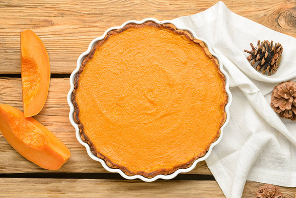Baking dish with tasty pumpkin pie on wooden background - Zdjęcie, obraz