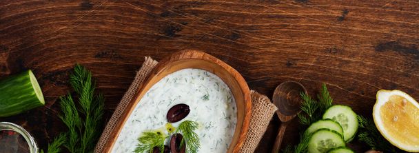 Traditional Greek sauce Tzatziki in olive wooden bowl on old rustic background. Top view. - Foto, Imagem