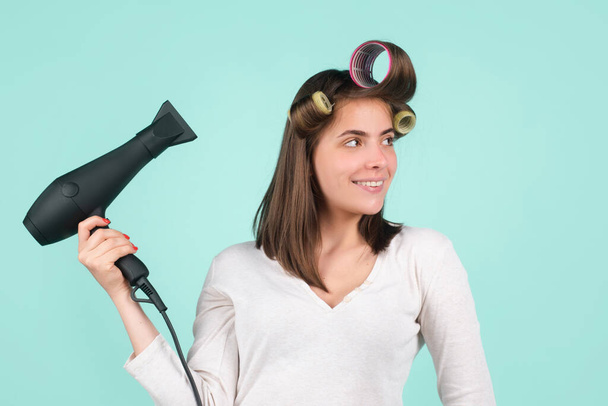 Woman with hair dryer. Beautiful girl with straight hair drying hair with professional hairdryer. Isolated on blue background. - Fotoğraf, Görsel