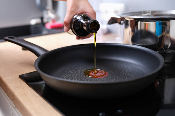 Chef pouring olive oil into frying pan in kitchen closeup - Fotoğraf, Görsel