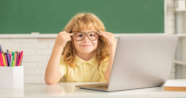 allegro ragazzo in occhiali studio online a scuola classrrom con computer portatile, settembre - Foto, immagini