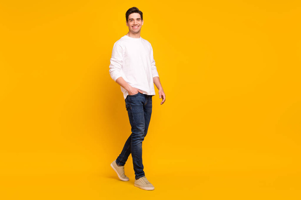 Full size profile photo of funny brunet young guy go wear shirt jeans sneakers isolated on yellow color background - Foto, Imagen