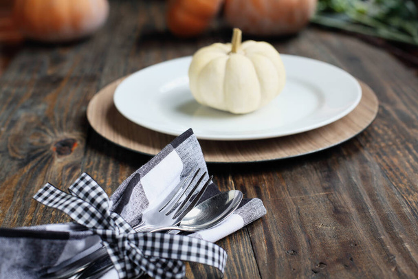 Silverware on Thanksgiving Day holiday table buffalo check napkin tied with black and white bow. Selective focus on for and spoon with blurred foreground and background.  - Photo, Image