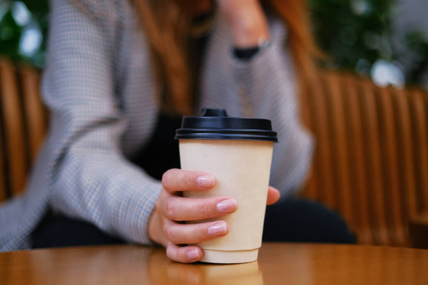 bela mulher segurando café em uma xícara de papel. Café para levar. menina beber chá no terraço - Foto, Imagem