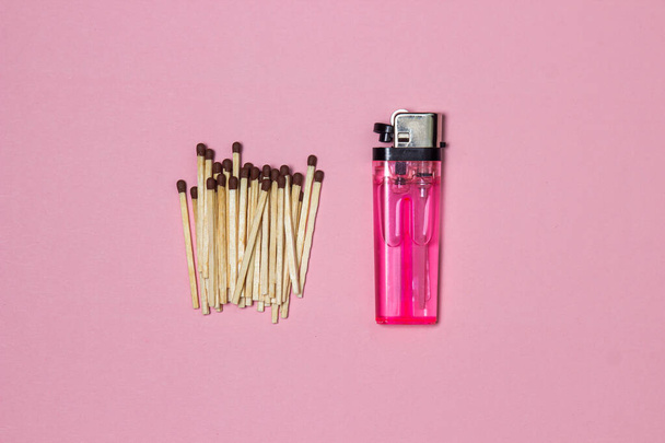 Matches and a lighter on a pink background. Pink plastic lighter - Φωτογραφία, εικόνα