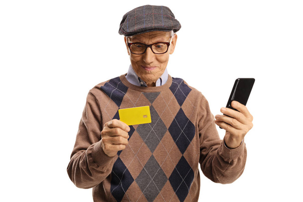 Cheerful elderly man using a smartphone and a credit card isolated on white background - Valokuva, kuva