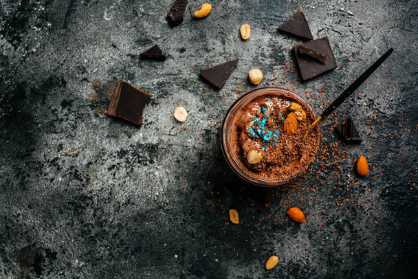 zelfgemaakte chocolade ijs besprenkeld met chocolade in een glazen pot op donkere achtergrond, banner, menu, recept plaats voor tekst, bovenaanzicht. - Foto, afbeelding
