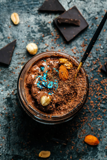 Hausgemachtes Bio-Schokoladeneis mit Nüssen auf dunklem Hintergrund, Lebensmittelrezept Hintergrund. Nahaufnahme. - Foto, Bild