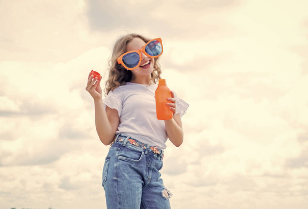 kid beauty and fashion. child hold bottle of water. Child on the background of sky. summer holiday concept. childhood happiness. happy childrens day. drinking fresh juice - Foto, imagen