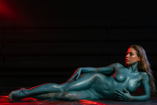 Gorgeous naked brunette posing painted in turquoise sequins. - Foto, Imagem