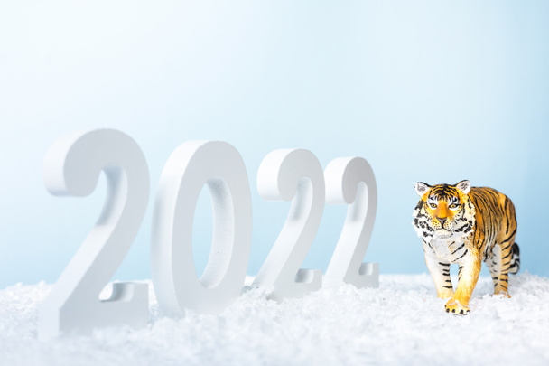 Happy New Year 2022. Decorative white number 2022 and figurine of tiger isolated on blue background. Christmas greeting card. - Photo, Image