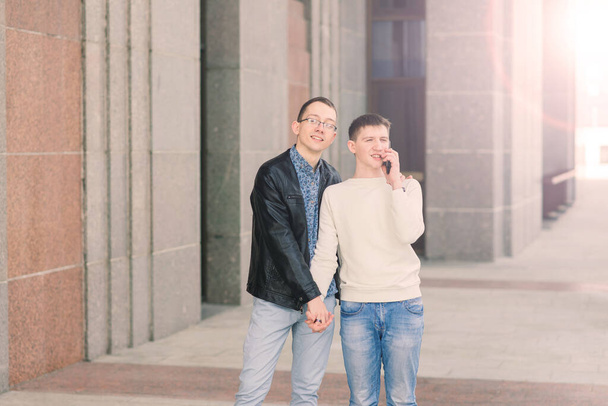 Χαριτωμένο γκέι ζευγάρι σε μια πόλη, τρυφερό απαλό φιλί, χαμογελαστό - Φωτογραφία, εικόνα