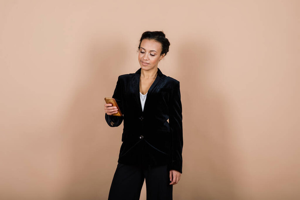 Een geïsoleerde opname van een gelukkige zwarte zakenvrouw in studio, notebook, smartphone - Foto, afbeelding
