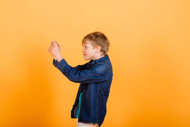 The little boy phones on yellow background - Φωτογραφία, εικόνα