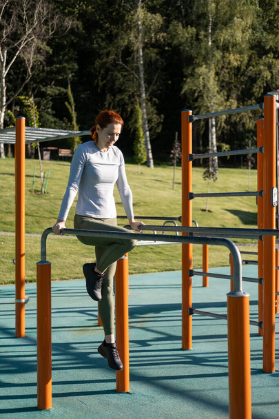 athletic ginger woman working out outdoor on urban sports ground in sunny autumn day. - Foto, immagini