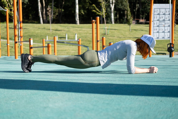 femme gingembre athlétique travaillant en plein air sur un terrain de sport urbain dans la journée ensoleillée d'automne. - Photo, image