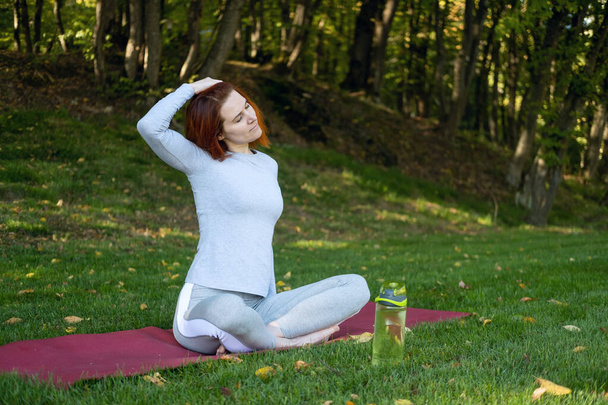 forme gingembre femme échauffement pour le yoga du matin en plein air sur le parc en automne journée ensoleillée. - Photo, image