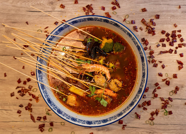 Traditioneller chinesischer Hot Pot, würziges Gericht mit Garnelen, Tofu, Brokkoli und anderem Gemüse - Foto, Bild