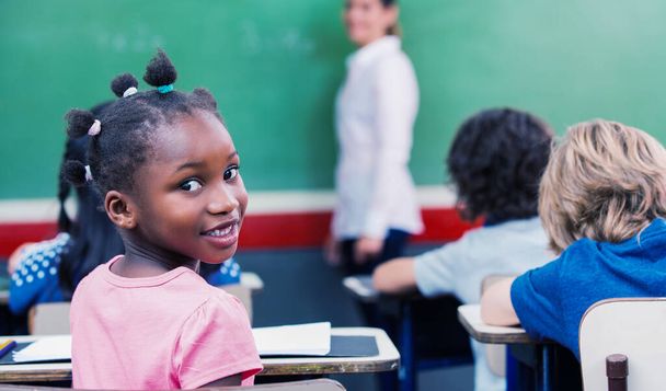 Afro amerikai iskolás lány mosolyog az óra alatt. - Fotó, kép