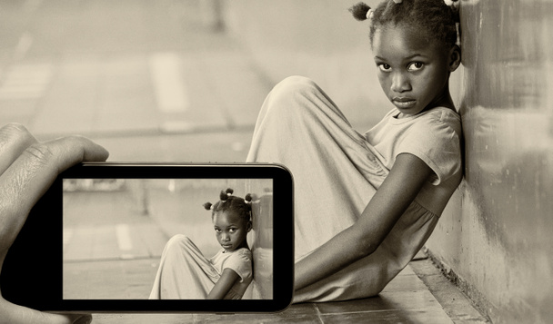 Женская рука со смартфоном фотографирует грустную девушку в начальной школе. Концепция запугивания
. - Фото, изображение