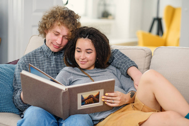 Young pregnant couple expecting a baby and looking to their family photo book. - Foto, Bild