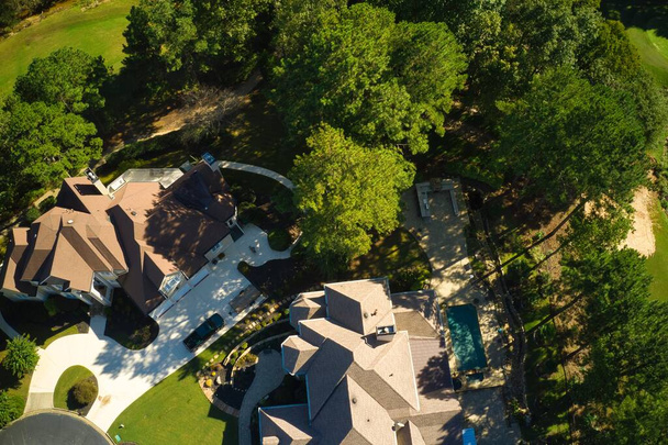 Vue panoramique aérienne du haut vers le bas de la grappe de maisons dans une subdivision de banlieue avec un terrain de golf et de beaux jardins filmés pendant l'heure dorée - Photo, image