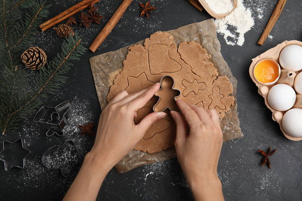 Woman making gingerbread Christmas cookies at black table, top view - Photo, image