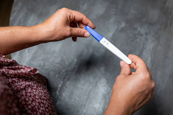 girl holding negative pregnancy test in her hands on gray background - Zdjęcie, obraz